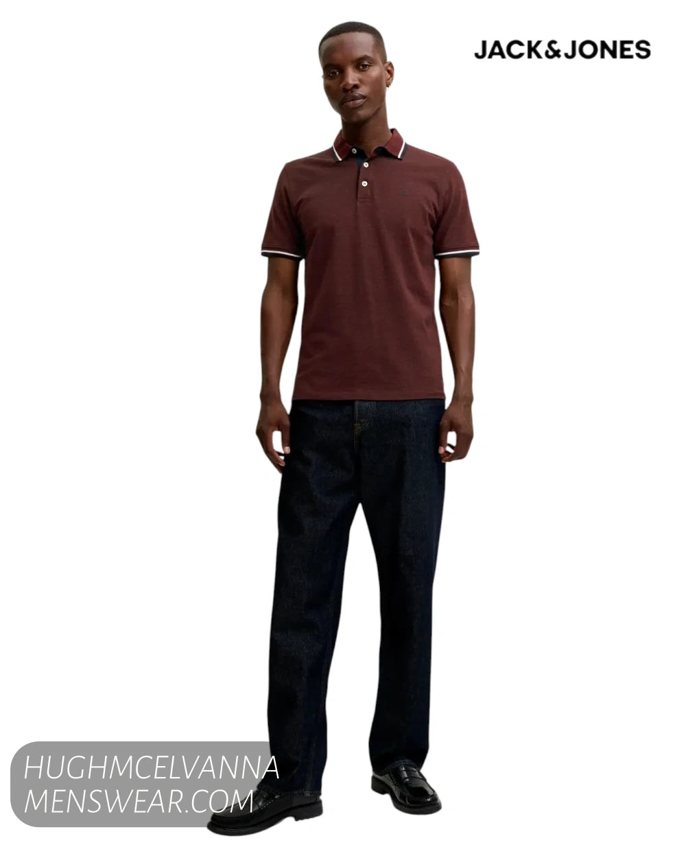 Full-length shot of a male model wearing a Jack and Jones fire brick red polo shirt, dark denim jeans, and black loafers.