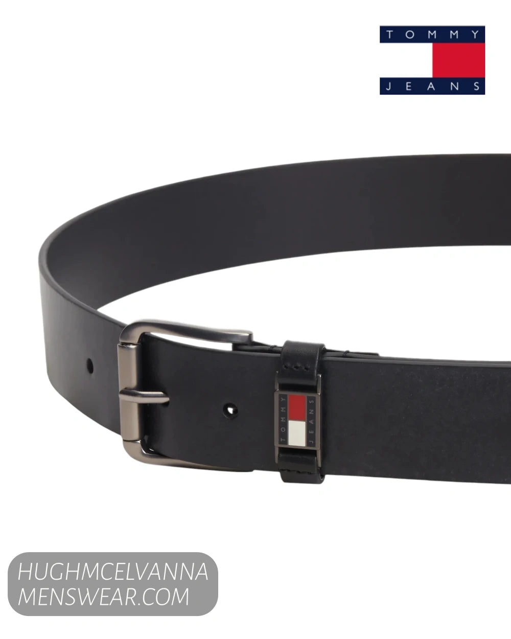 Angled close up view of Tommy Jeans black leather belt showing enamel flag badge on loop