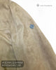 Close up detail of metal Lino Clemente diamond emblem on tan faux suede jacket sleeve