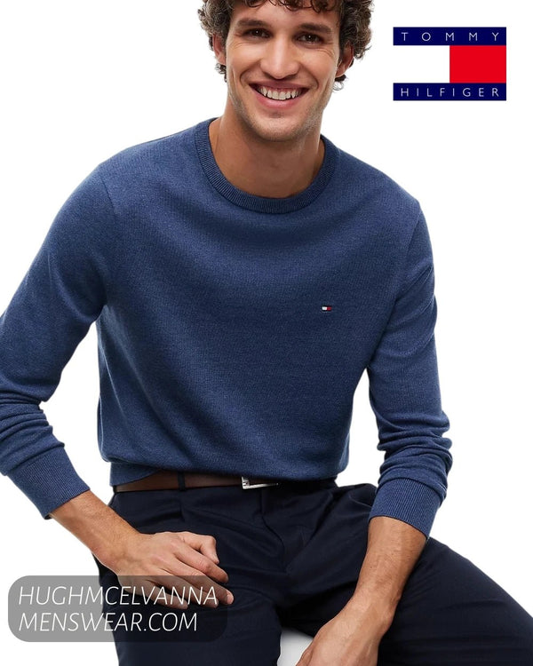 Seated smiling model wearing Tommy Hilfiger Aegean Sea cotton crew neck jumper showing regular fit profile