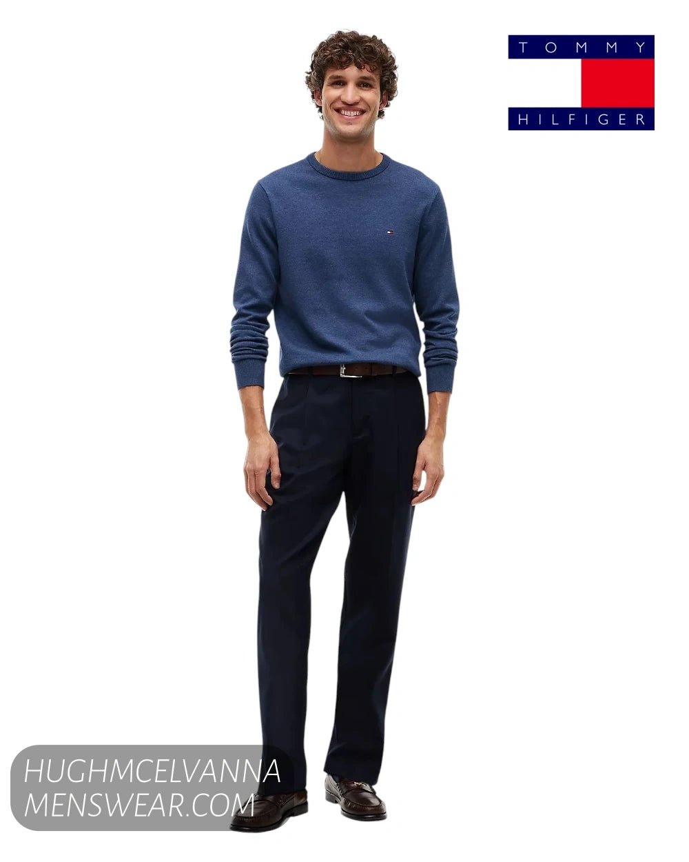 Full length model view wearing Tommy Hilfiger Aegean Sea blue jumper with navy trousers and brown loafers