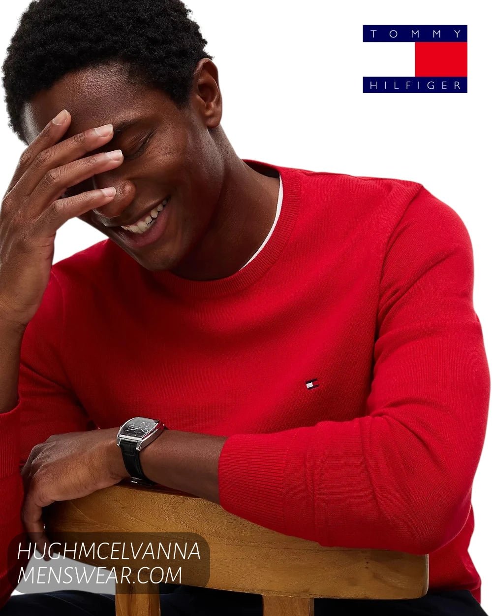 Seated model view wearing Tommy Hilfiger red cotton crew neck jumper highlighting ribbed cuffs and neckline
