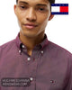 Close up front view of model wearing a Tommy Hilfiger burgundy micro-pattern shirt with white buttons and embroidered chest flag