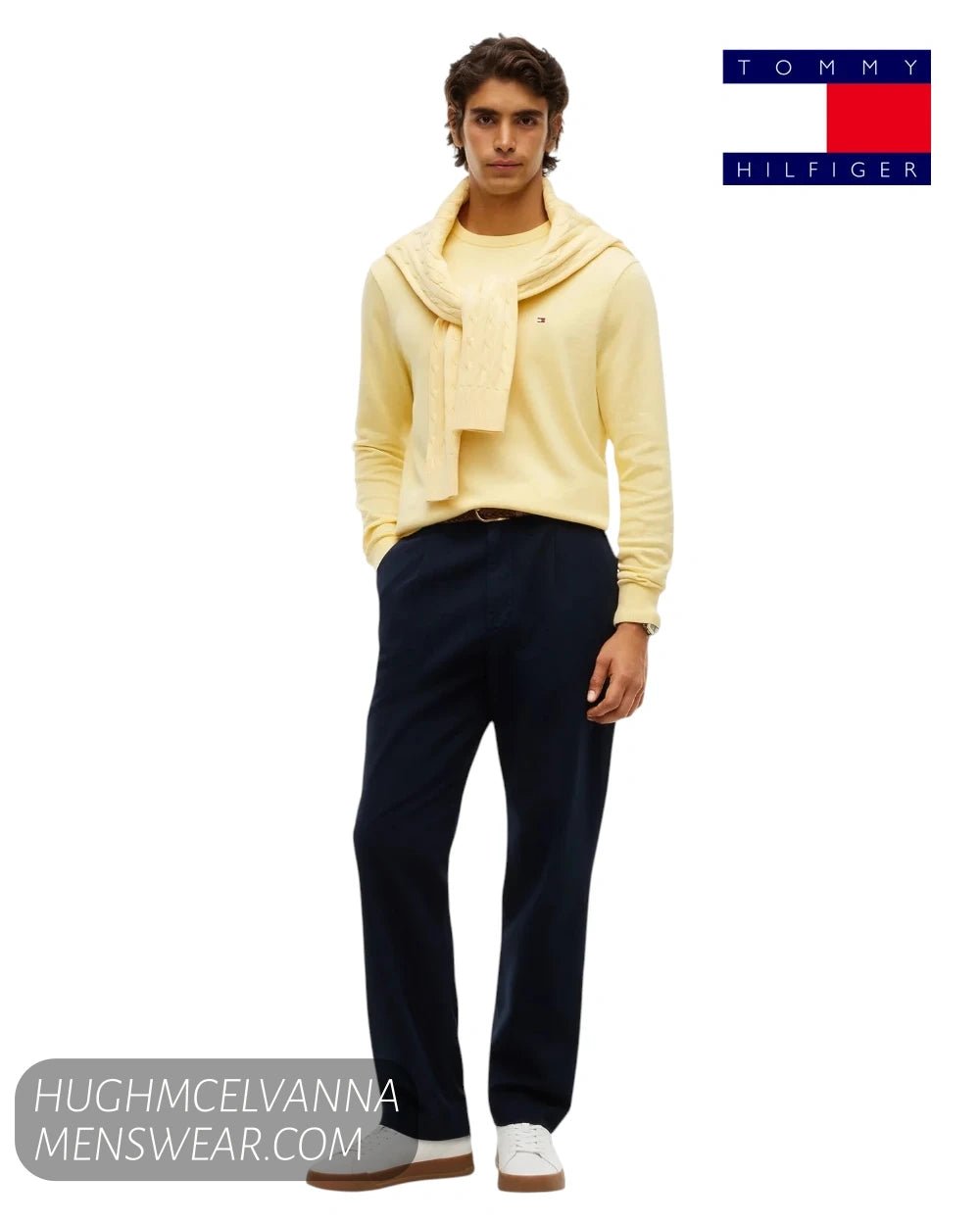 Full length model view wearing Tommy Hilfiger Light Daffodil yellow jumper with navy trousers and white trainers