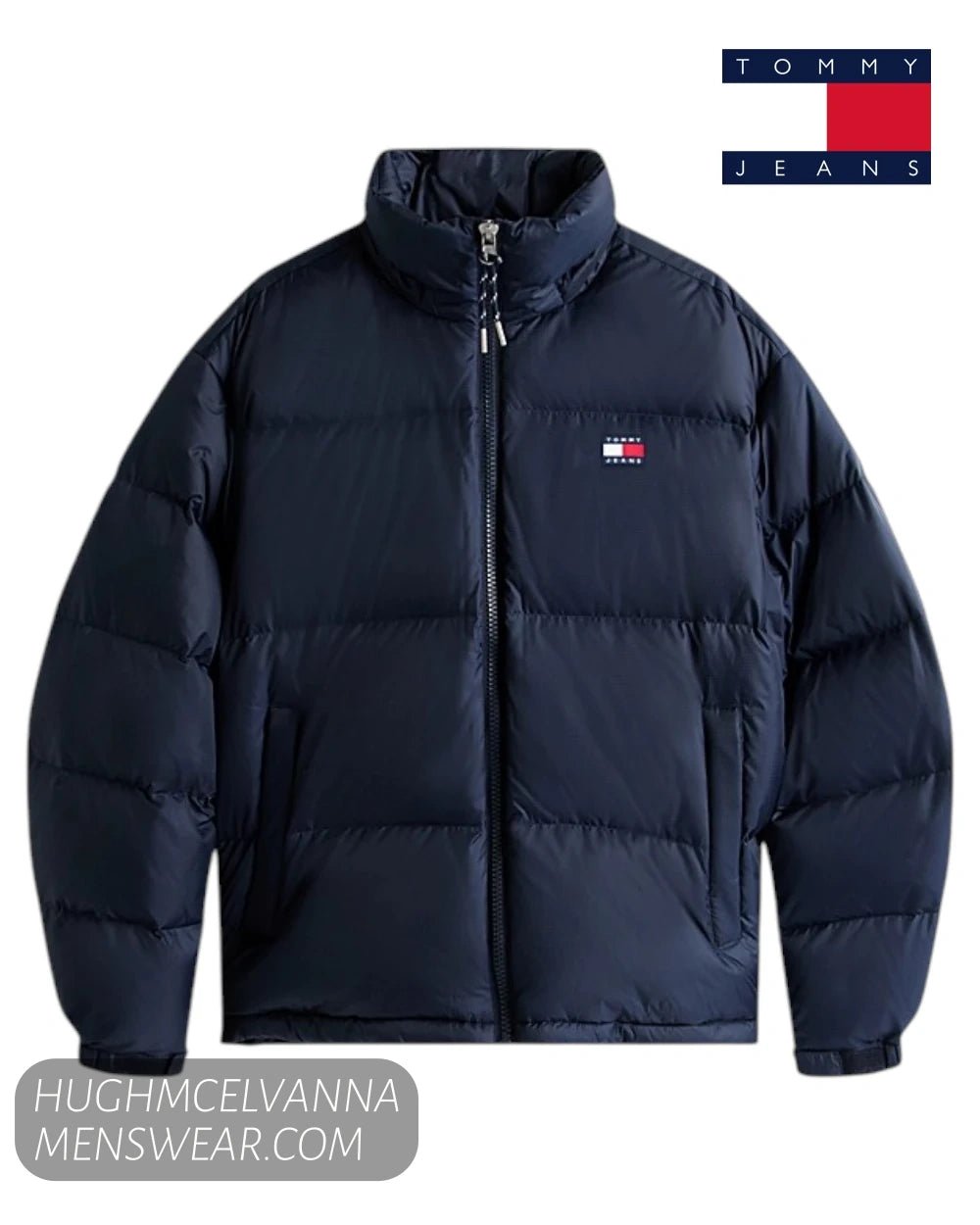 A navy blue Tommy Jeans puffer jacket with a high collar, front zipper, and the classic red, white, and blue Tommy Hilfiger flag logo embroidered on the left chest. 