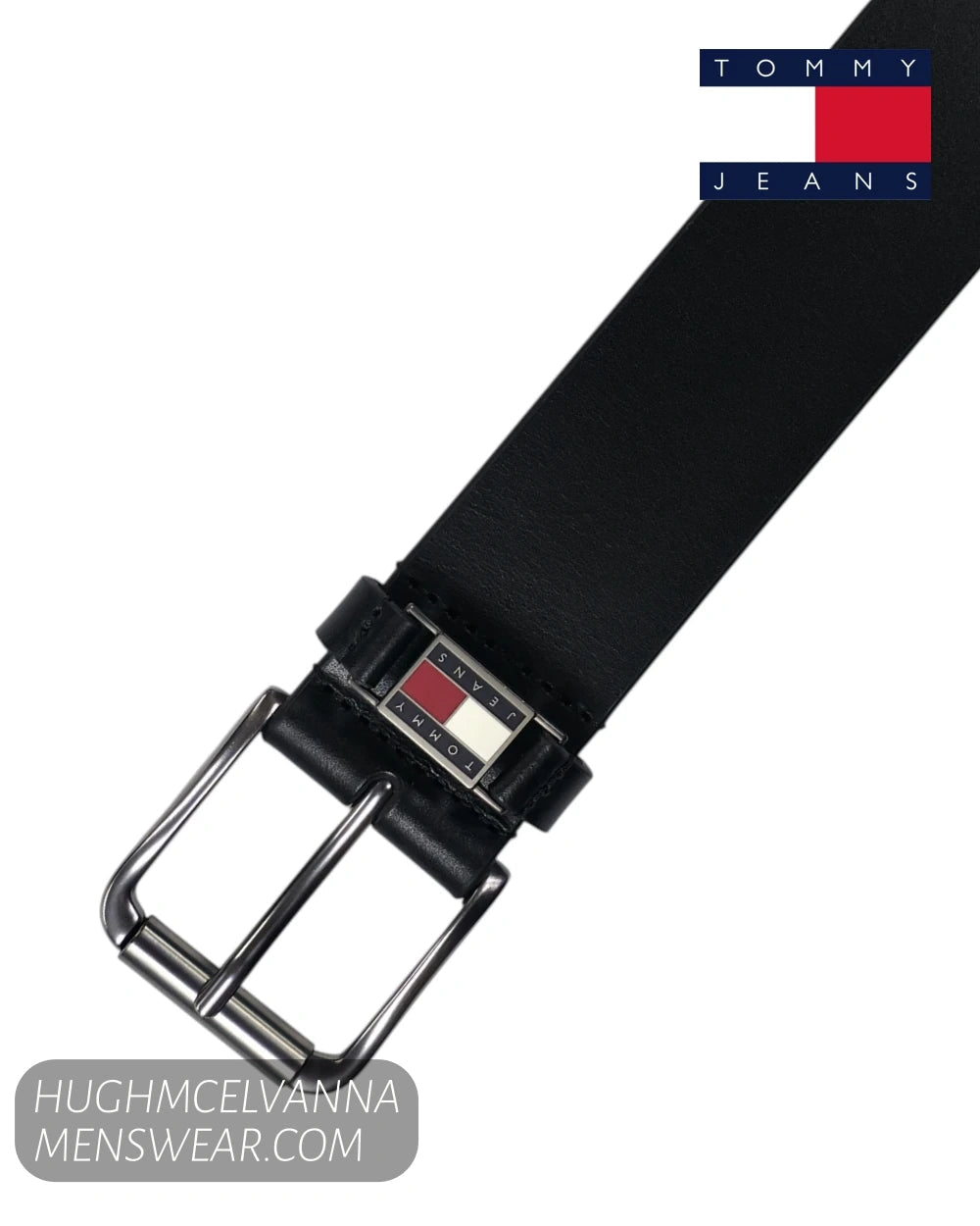 Tommy Jeans black leather belt with a silver-tone buckle and a small red, white, and blue logo accent on the buckle plate, shown on a white background with a Tommy Jeans logo in the top right.