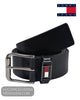 A black leather belt with a silver-tone buckle, coiled on a white background. The belt features a small Tommy Hilfiger flag emblem on the buckle keeper.