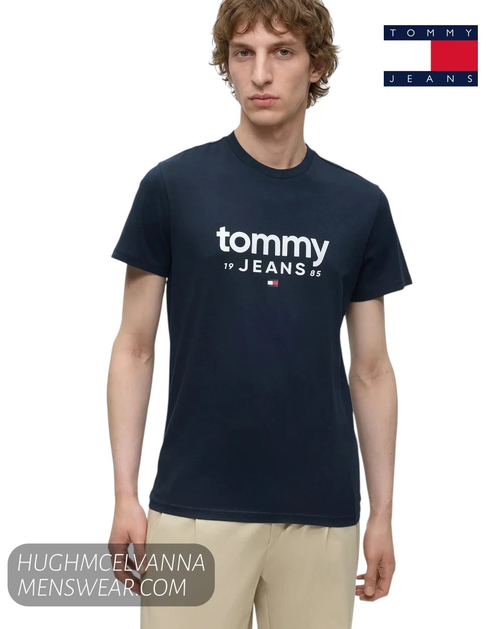 Half length view of model wearing Tommy Jeans navy graphic t-shirt with hands by his side