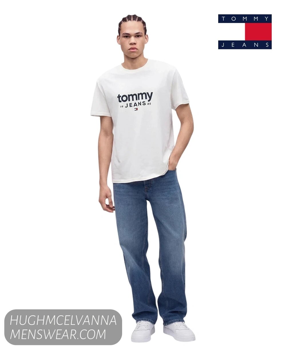 Full length studio model shot wearing Tommy Jeans white logo tee with relaxed blue jeans and white trainers