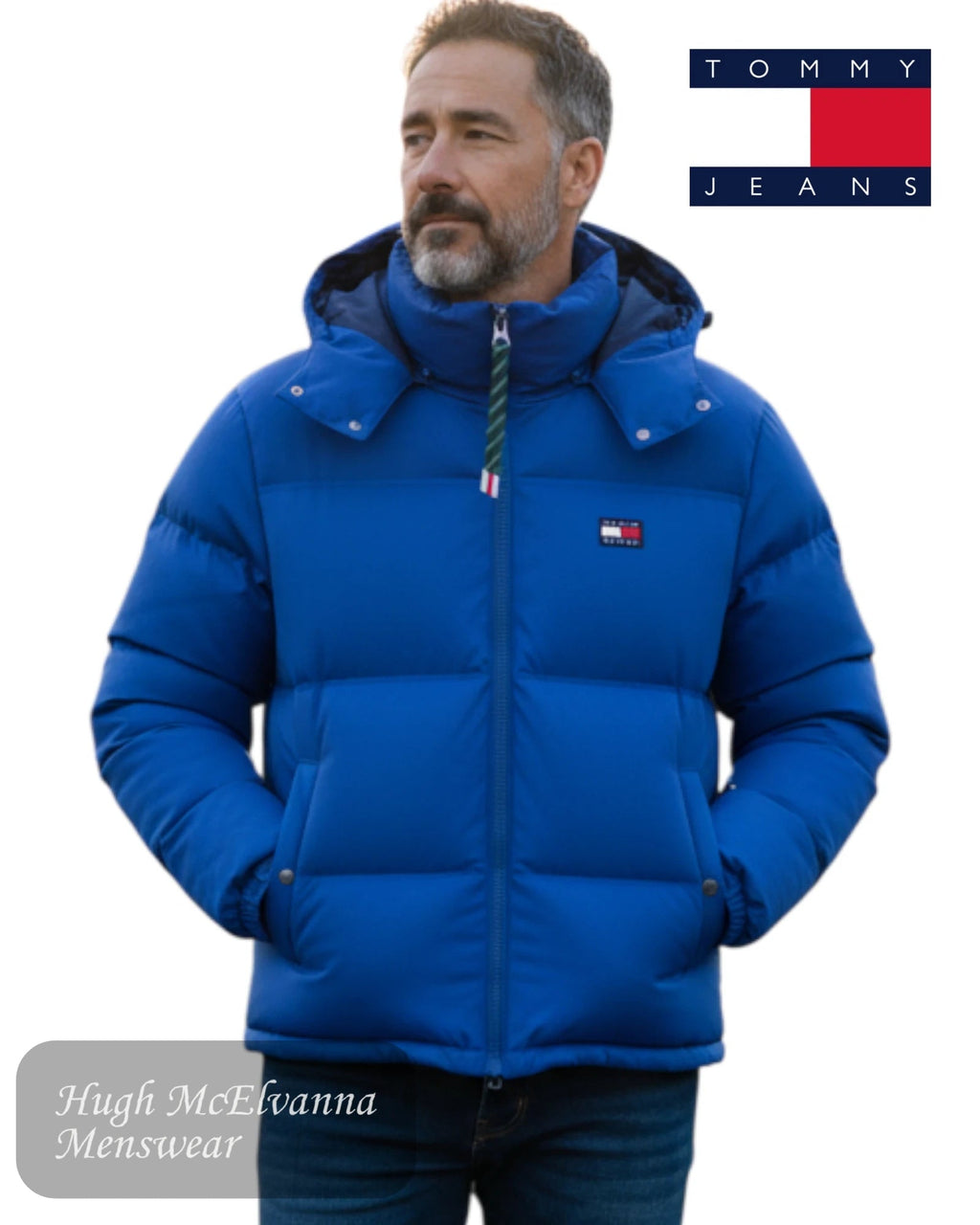Man wearing a blue puffer jacket with Tommy Jeans logo on a white background