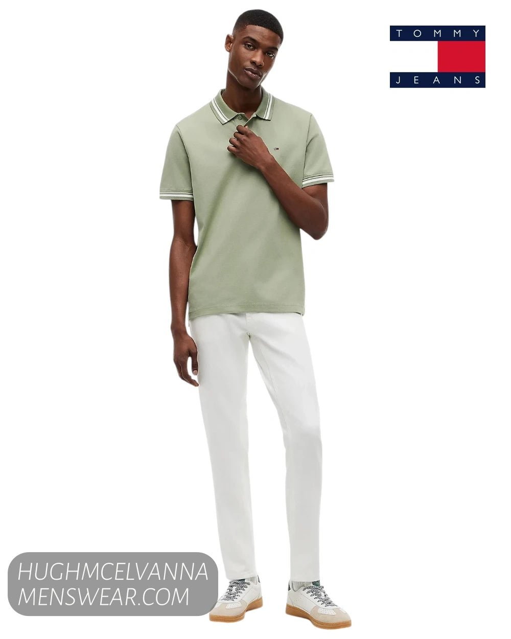 Full length studio shot of model wearing Tommy Jeans Spring Olive polo shirt with white jeans and trainers