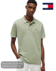 Mid shot of model wearing Tommy Jeans short sleeve tipped polo shirt in Spring Olive with hand in pocket