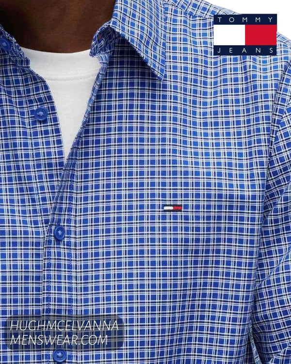 Close up detail of Tommy Jeans Providence Blue grid check cotton fabric, blue buttons, and embroidered chest flag badge