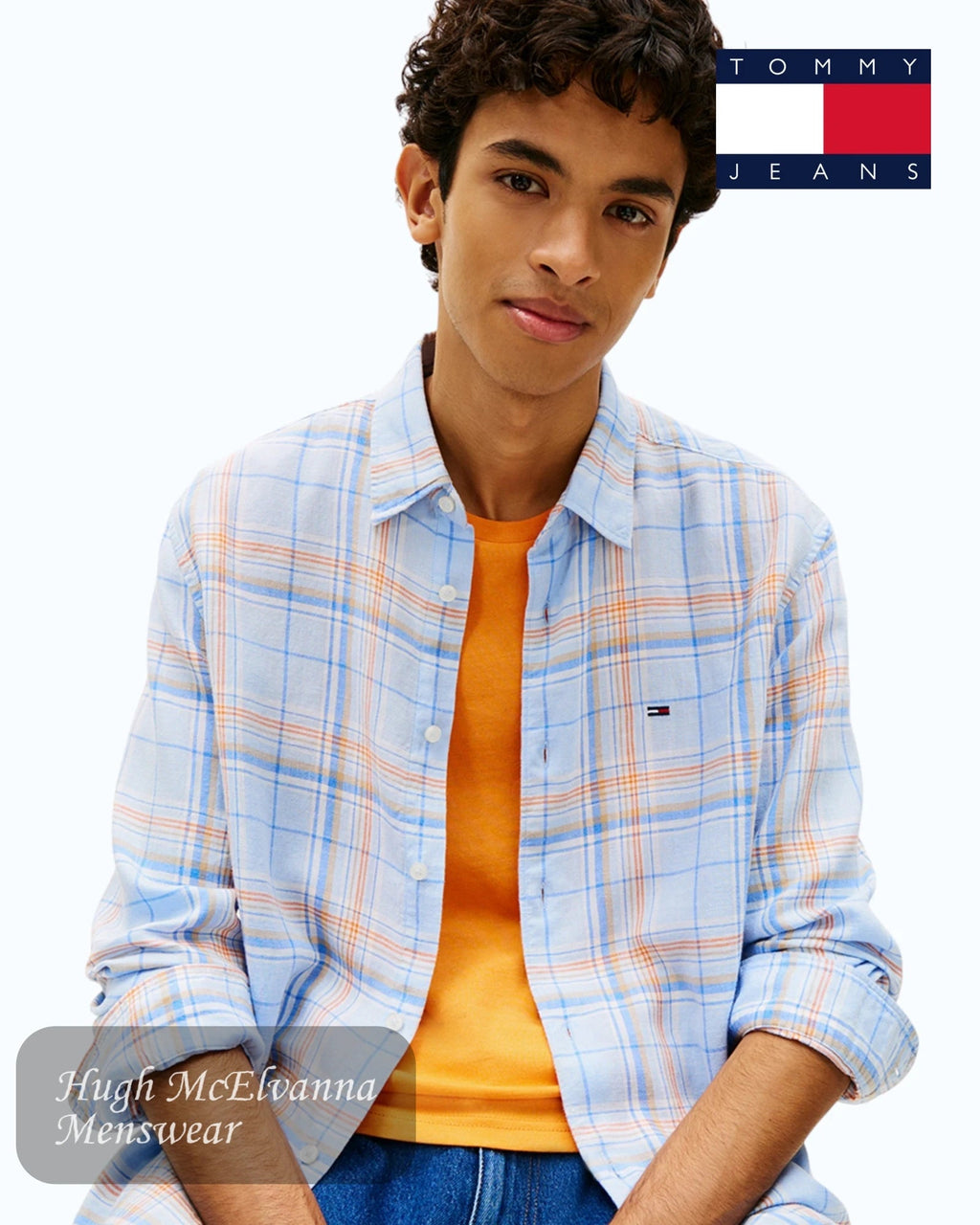 Model wearing Tommy Jeans relaxed fit linen shirt with blue and orange checkered pattern and classic collar. DM0DM22758-C3Q